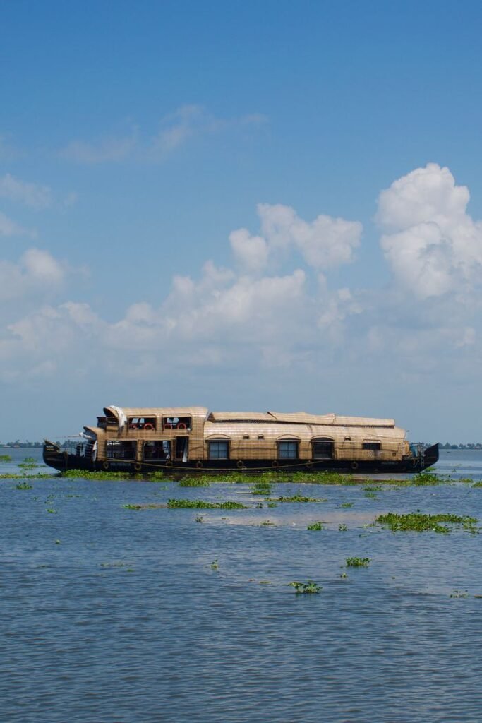 pexels photo 18633282 A traditional houseboat cruises on a serene lake under a clear blue sky, offering a tranquil experience.