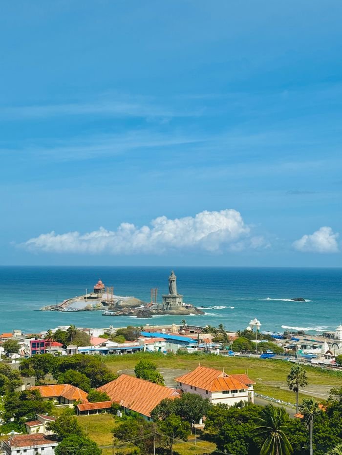 Aerial view of Vivekananda Rock, ocean, and coastal town under a clear blue sky.