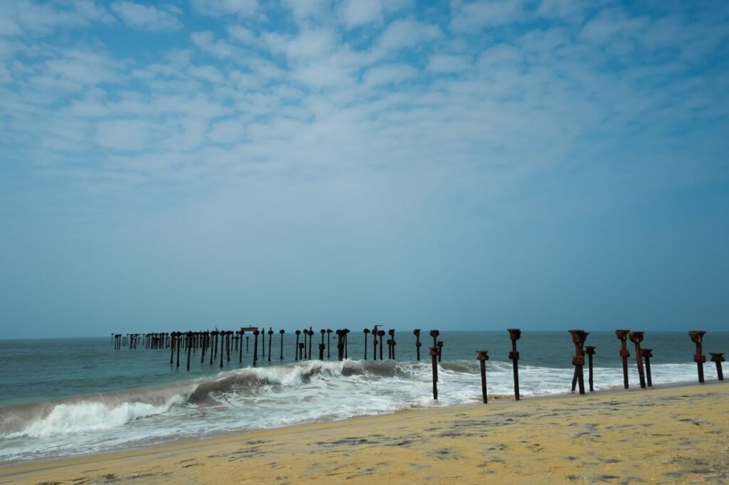 ALLEPPEY & MUNNAR Experience the serene beauty of Alappuzha Beach with its unique piers against a clear blue sky.