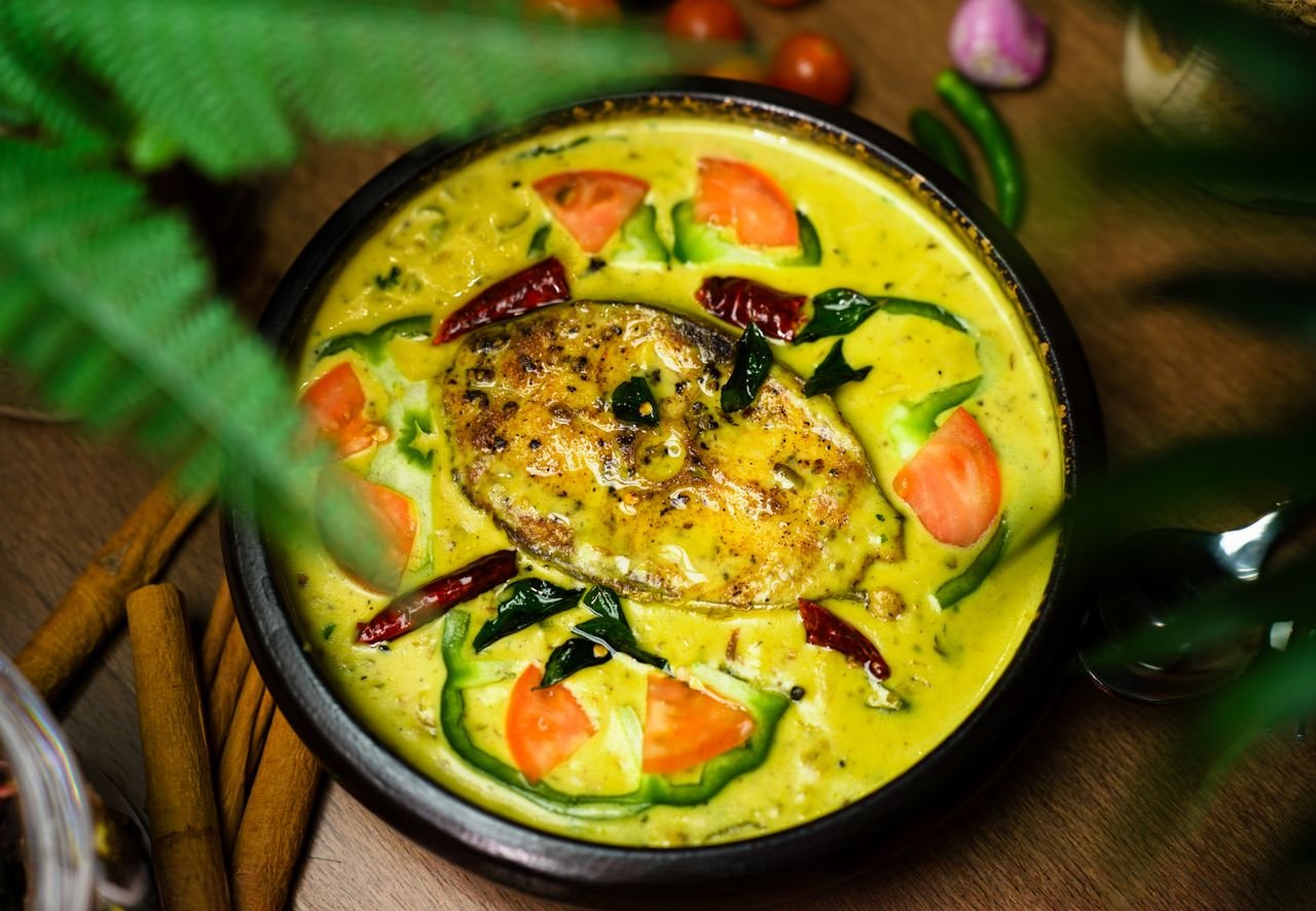 services-01 Vibrant Indian fish curry dish garnished with fresh vegetables and spices.